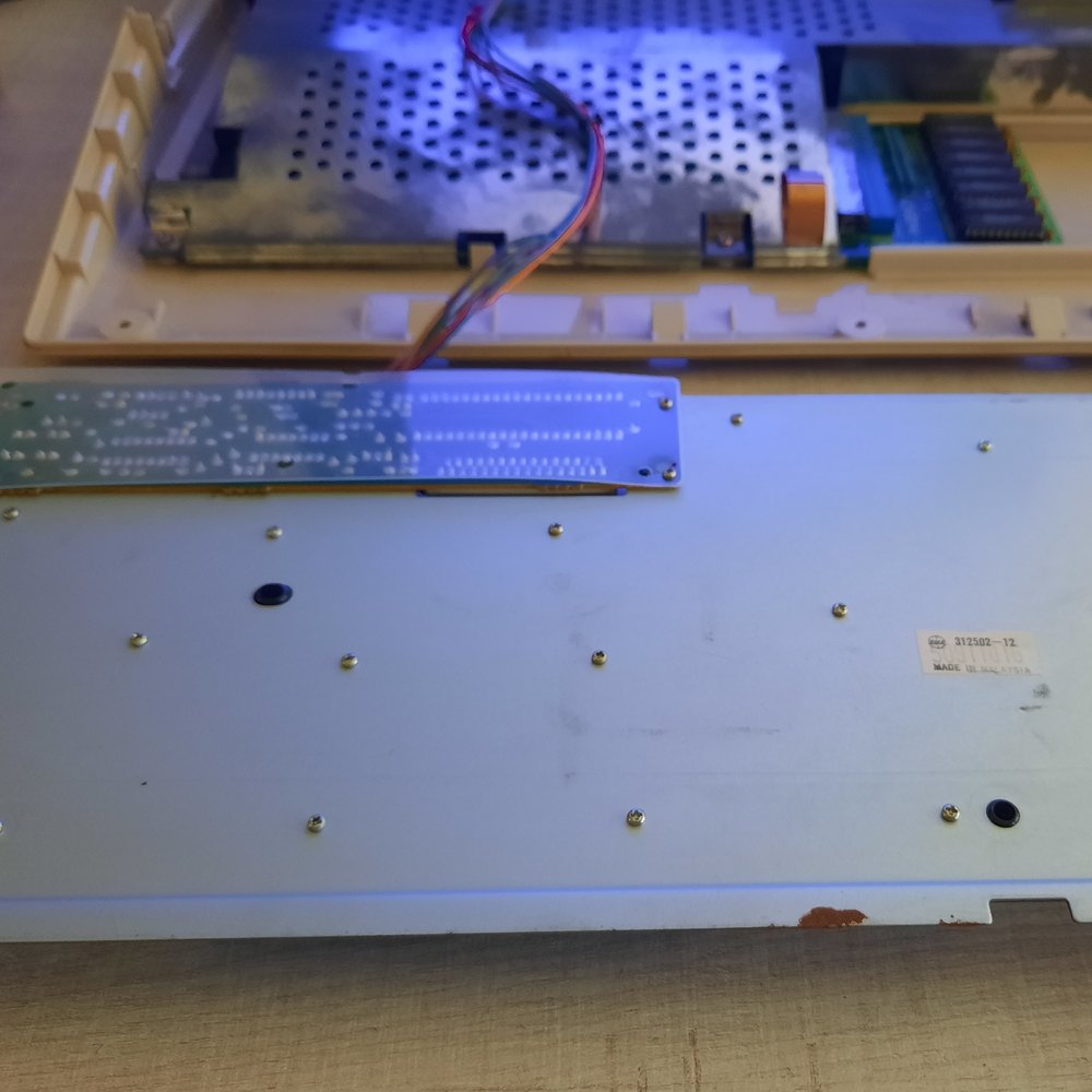 The back of an Amiga 500 keyboard with the back plate and controller visible